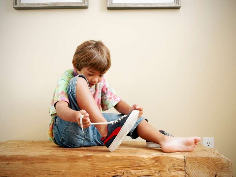 A boy tying his shoe lace